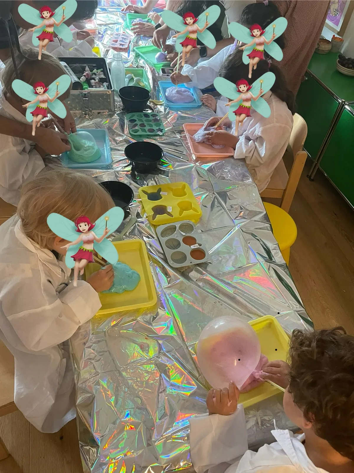 Workshop: Kinder in Laborkitteln an einem glitzernden Tisch mit Slime, Farben und Experimenten